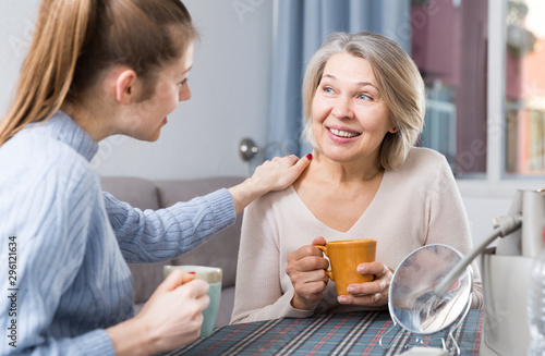 Mature mom talks to adult daughter at the table. Tea party © JackF