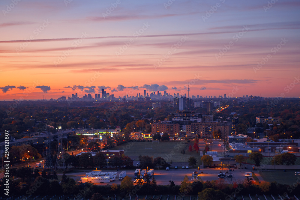 Beautiful pink yellow purple morning sky clouds in Toronto city, Canada. Rays of early rising sun. Landscape aerial top view with urban street. Twilight in Canadian metropolia at sunrise or sunset.