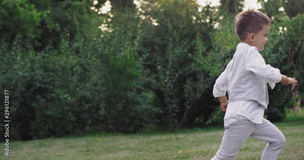 Charismatic 5 years boy running very enthusiastic and looking to the camera in the middle of a large green park Charismatic 5 years boy running very enthusiastic and looking to the camera in the middle of a large green park