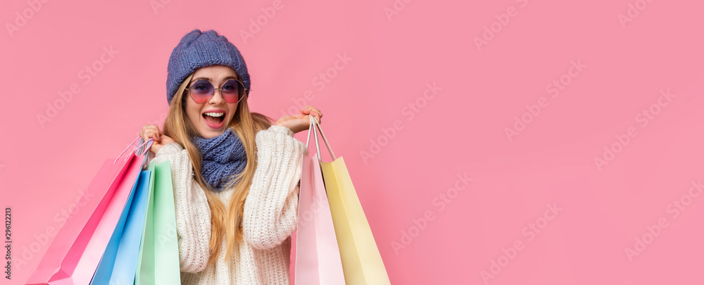 Fototapeta premium Excited girl in knitted hat and sunglasses with shopping bags