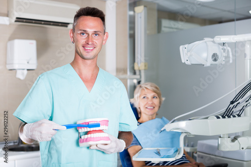 Dentist explaining teeth brushing on dental model