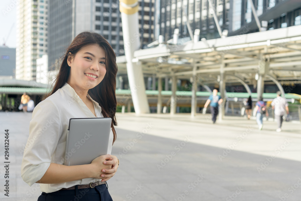 Professional business woman smiling holding laptop working to outdoor city.