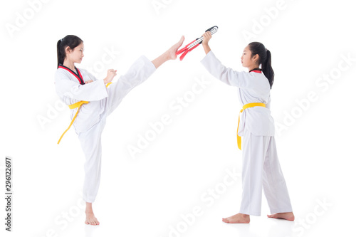 Two young asian girls having taekwondo training ,one girl kicking while other one holding kick target over white background.