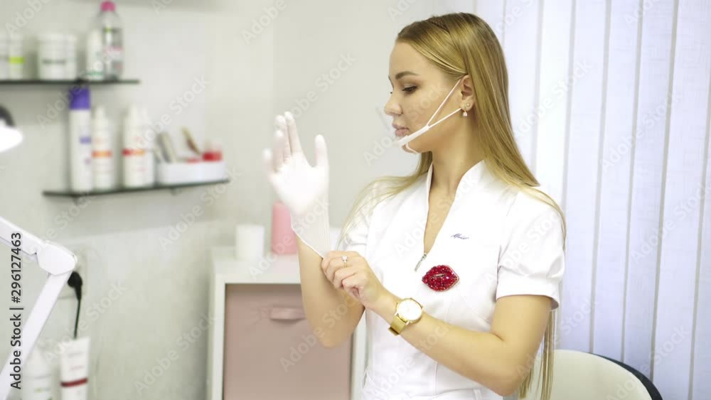 Beautiful woman beautician in a beauty salon puts on gloves. Beautiful woman beautician in a beauty salon puts on gloves.