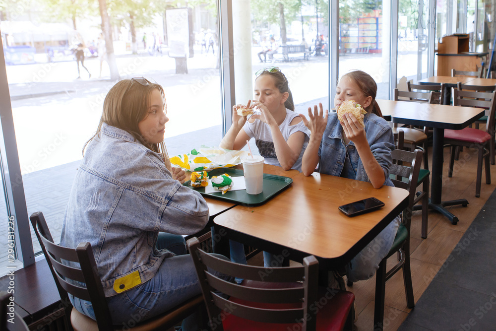 Girls Teenagers at a table in a cafe eat sandwiches and drink soda. Girls Teenagers at a table in a cafe eat sandwiches and drink soda.