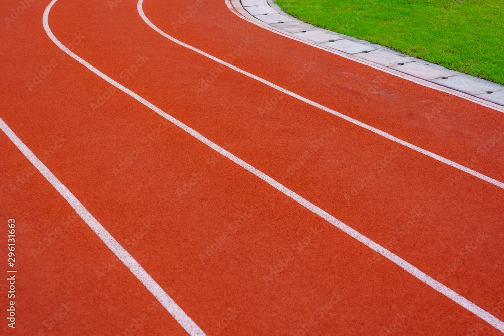 Red running track or resin Emboss Topping with white lines in outdoor sport stadium, side is a field and park. Backgrounds and rubber texture.