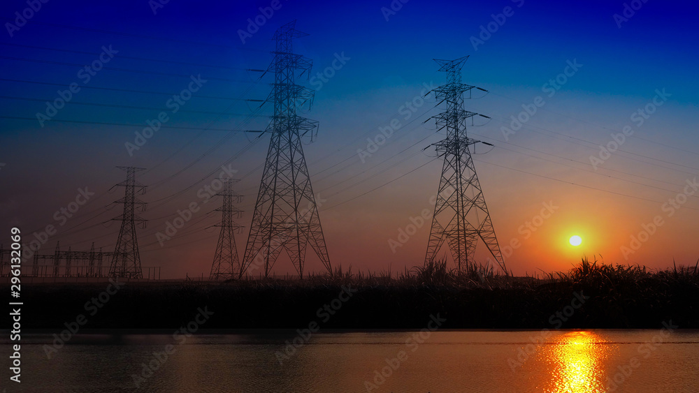 high voltage post or high voltage tower electric transmission tower system with sky sunset silhouette near pond in the evening,landscaping shot photo.