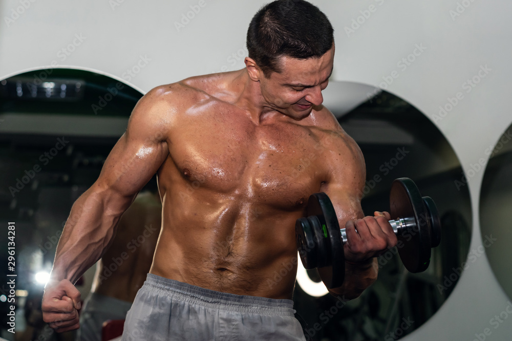 muscular bodybuilder doing exercise on bars in the gym. a handsome, sporty, sexy guy with a abs training in the gym. fitness, bodybuilding, nutrition, healthy lifestyle