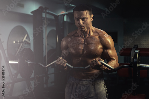 muscular bodybuilder doing exercise on bars in the gym. a handsome, sporty, sexy guy with a abs training in the gym. fitness, bodybuilding, nutrition, healthy lifestyle photo