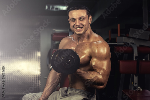 muscular bodybuilder doing exercise on bars in the gym. a handsome, sporty, sexy guy with a abs training in the gym. fitness, bodybuilding, nutrition, healthy lifestyle photo