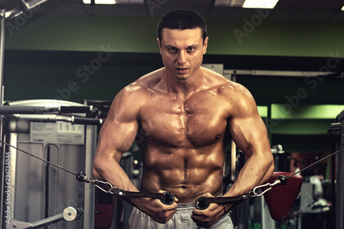 muscular bodybuilder doing exercise on bars in the gym. a handsome, sporty, sexy guy with a abs training in the gym. fitness, bodybuilding, nutrition, healthy lifestyle