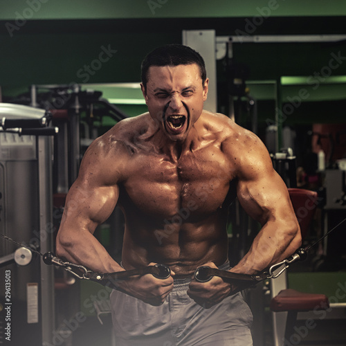 muscular bodybuilder doing exercise on bars in the gym. a handsome, sporty, sexy guy with a abs training in the gym. fitness, bodybuilding, nutrition, healthy lifestyle