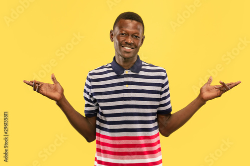 Nice to meet you. Young african-american man isolated on yellow studio background, facial expression. Beautiful male half-lenght portrait. Concept of human emotions, facial expression. Looking