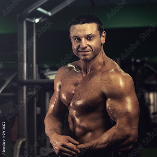 muscular bodybuilder doing exercise on bars in the gym. a handsome, sporty, sexy guy with a abs training in the gym. fitness, bodybuilding, nutrition, healthy lifestyle