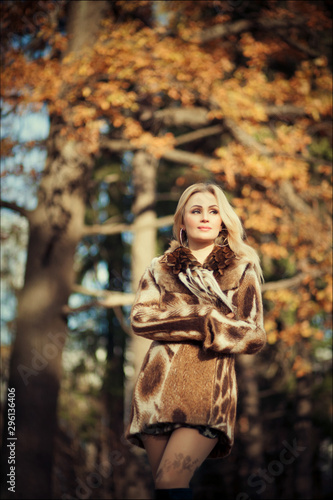 Outdoor fashion art photo of young beautiful blonde woman surrounded autumn leaves outdoor in park. Autumn season fashion concept
