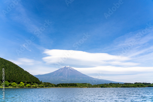 Fuji mountain with cloudy hat on top , fantastic clouds blue sky background spot view at Lake Tanuki (Tanuki-ko) in morning time near small hill and green forest foreground, Fujinomiya Shizuoka Japan.