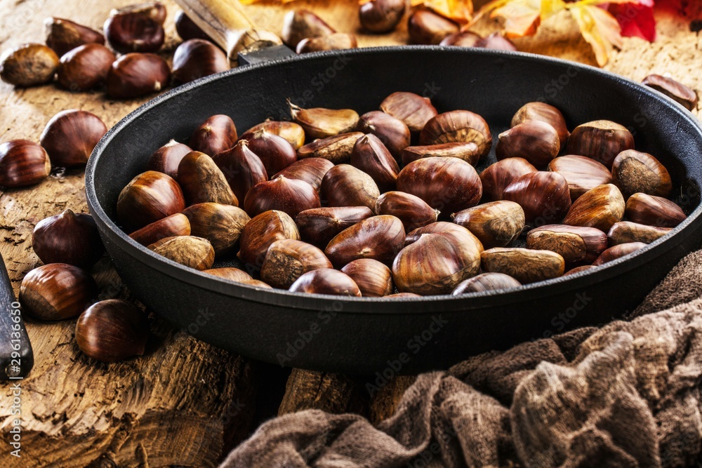 Roasted chestnuts served in chestnut pan on an old table Roasted chestnuts served in chestnut pan on an old table