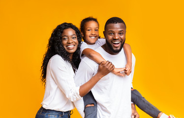 Young african american parents spending time with their little daughter