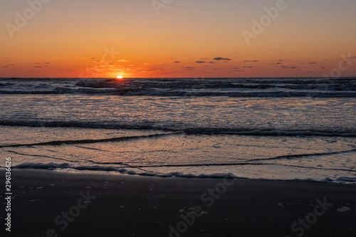 Beautiful sunset landscape at the North sea and orange sky with awesome sun golden reflection on waves as a background. Amazing summer sunset view on the beach.