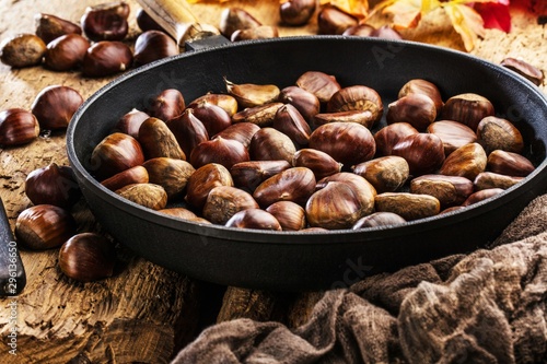 Roasted chestnuts served in chestnut pan on an old table