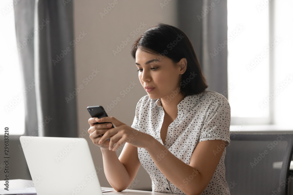 Serious Asian businesswoman using mobile phone at workplace Serious Asian businesswoman using mobile phone at workplace