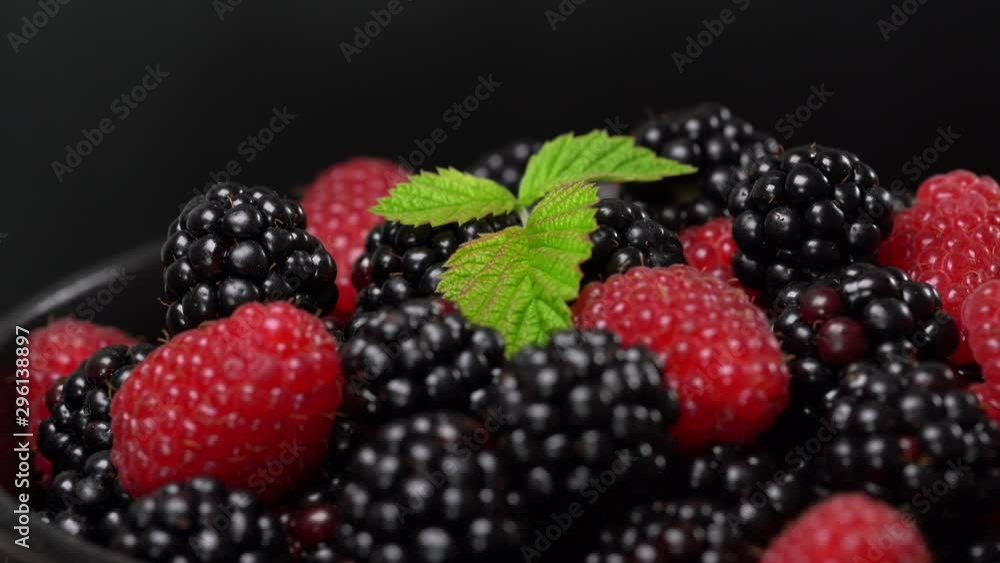 Background from fresh organic blackberries and raspberries. Lot of ripe juicy wild fruit raw berries on a plate rotates. Blackberry and raspberry, close up Background from fresh organic blackberries and raspberries. Lot of ripe juicy wild fruit raw berries on a plate rotates. Blackberry and raspberry, close up
