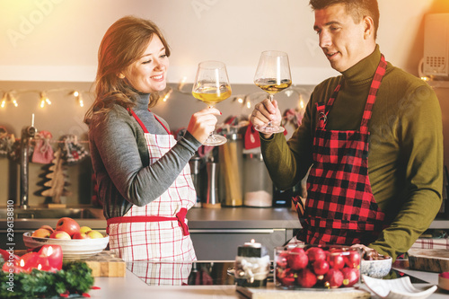 Couple celebrating Christmas in the kitchen and drink wine