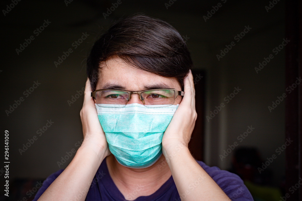 Ill Asian man with eyeglasses wearing hygienic mask feeling headache Ill Asian man with eyeglasses wearing hygienic mask feeling headache