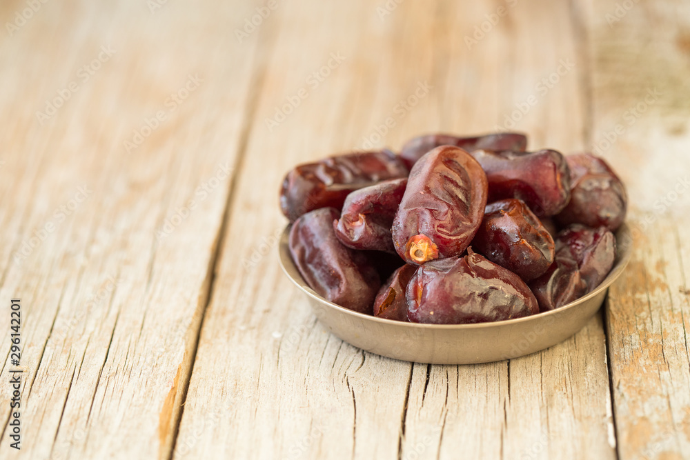 Dates on plate on wooden background, top view, copy space. Organic dried dates fruits.