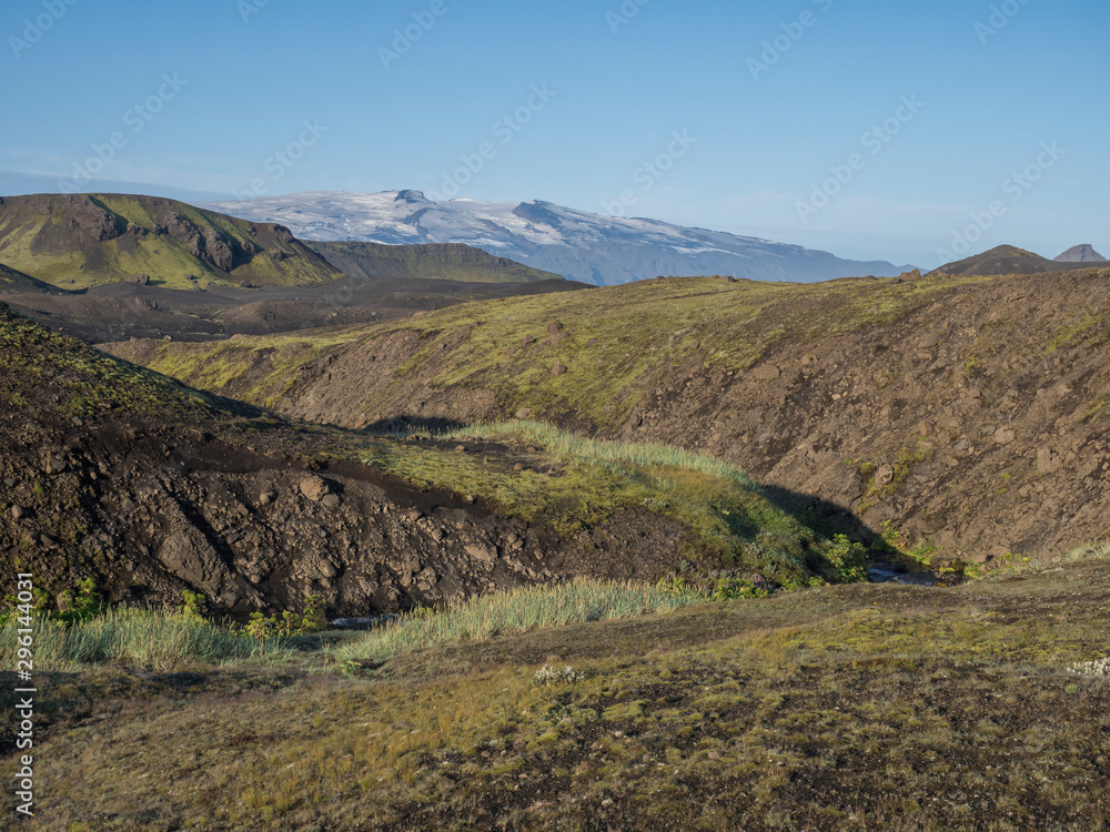 Icelandic landscape with eyjafjallajokull glacier tongue, blue river stream and green hills. Fjallabak Nature Reserve, Iceland. Summer blue sky