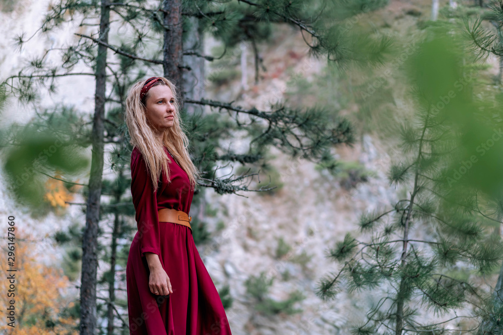 Girl in a burgundy dress in a pine forest. Girl in a burgundy dress in a pine forest.