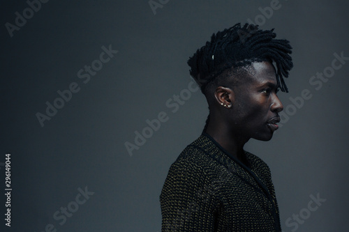 Profile portrait of a young man on dark black studio background