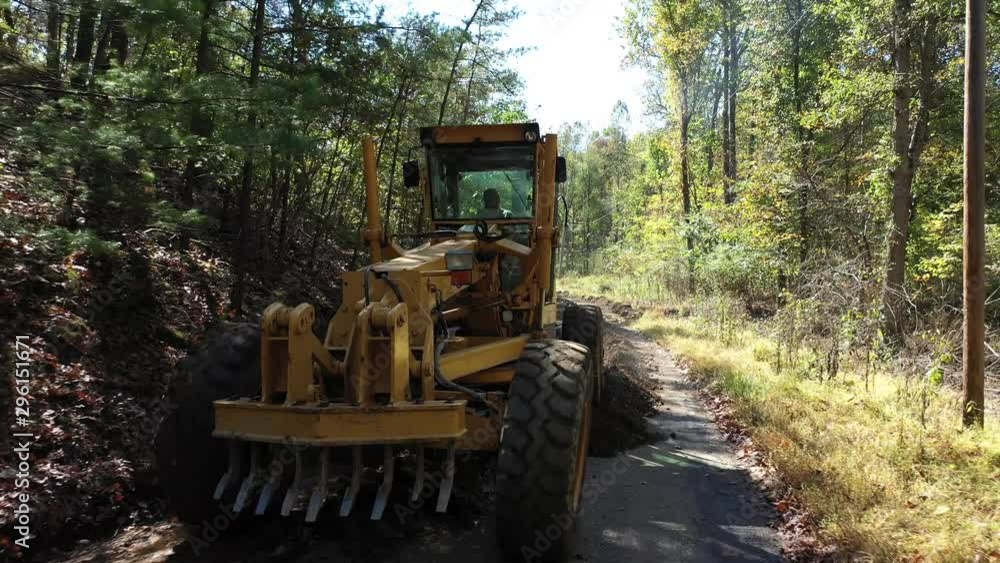 Low aerial shot or road grader scraping dirt making a new road. Low aerial shot or road grader scraping dirt making a new road.