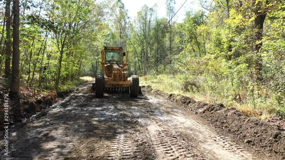 Low aerial shot or road grader scraping dirt making a new road. Low aerial shot or road grader scraping dirt making a new road.