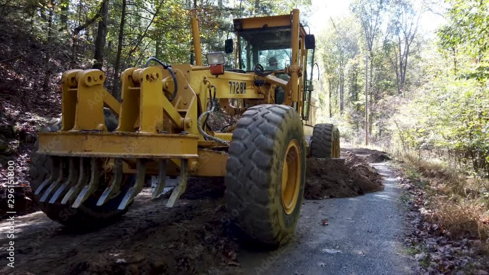Closeup of front wheels of road grader as it scrapes fresh dirt to make a road. Closeup of front wheels of road grader as it scrapes fresh dirt to make a road.