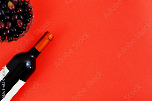Bottle of red wine near bunch of grapes