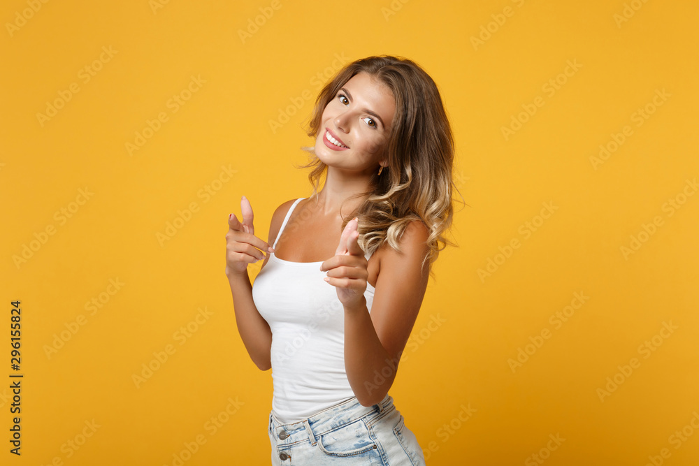 Smiling young woman girl in light casual clothes posing isolated on yellow orange wall background, studio portrait. People lifestyle concept. Mock up copy space. Pointing index fingers on camera. Smiling young woman girl in light casual clothes posing isolated on yellow orange wall background, studio portrait. People lifestyle concept. Mock up copy space. Pointing index fingers on camera.