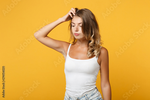 Preoccupied young woman girl in light casual clothes posing isolated on yellow orange wall background studio portrait. People lifestyle concept. Mock up copy space. Put hand on head, looking down.