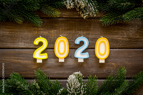2020 New Year design. Date laid out by candles near fir branches on dark wooden background top view © 9dreamstudio