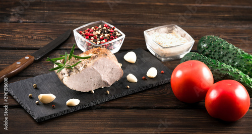 .smoked meat with tomatoes and cucumbers on a wooden background