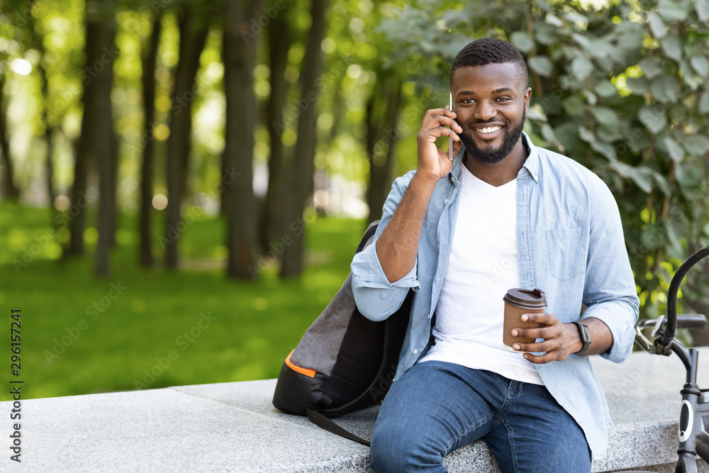 Handsome black guy talking on phone while drinking coffee outdoors Handsome black guy talking on phone while drinking coffee outdoors