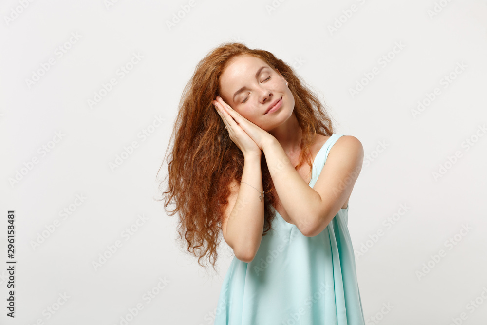 Young relaxed redhead woman in casual light clothes posing isolated on white background in studio. People sincere emotions lifestyle concept. Mock up copy space. Sleep with folded hands under cheek.