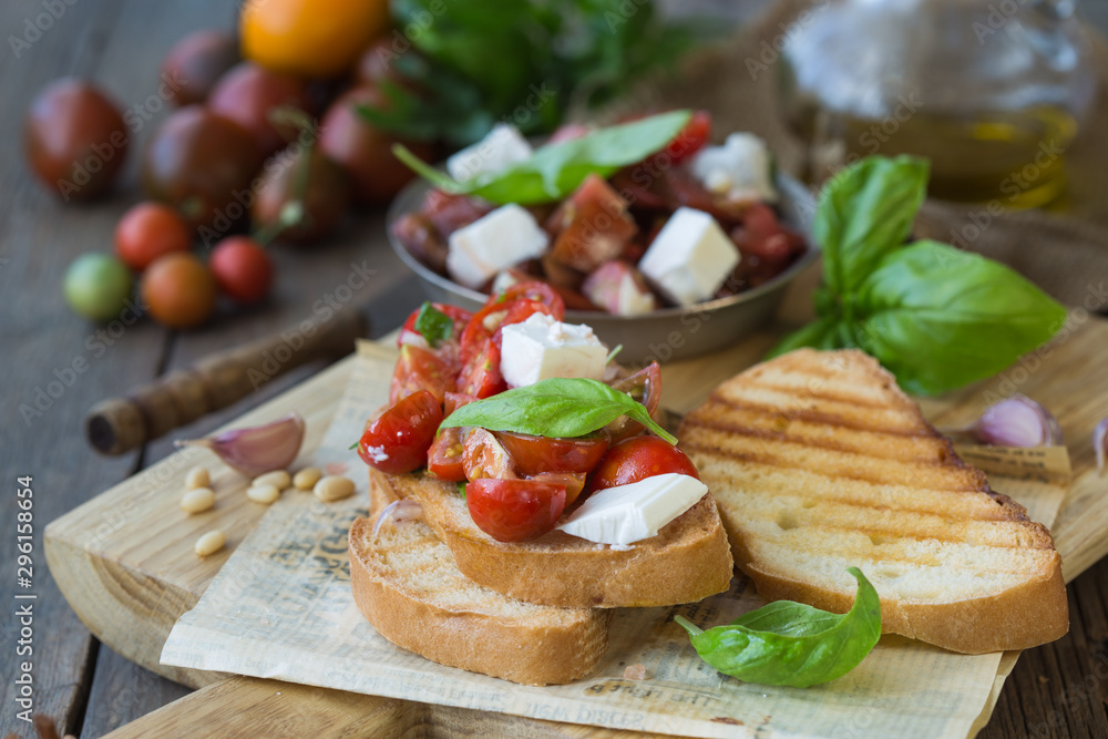 Bruschetta with tomatoes, mozzarella cheese and basil on a cutting board. Traditional italian appetizer or snack, antipasto.