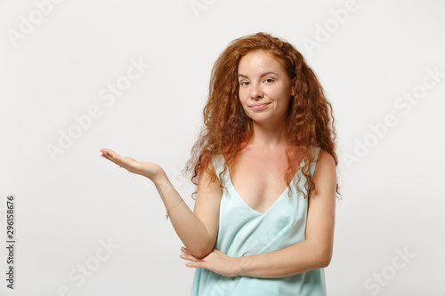 Young smiling pretty redhead woman girl in casual light clothes posing isolated on white background studio portrait. People sincere emotions lifestyle concept. Mock up copy space. Pointing hand aside.