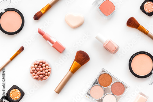 Makeup set with powder, rouge and brusheson white background top view pattern