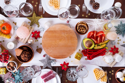 Christmas table setting with food on a plate and decoration on dark wooden table, flat lay