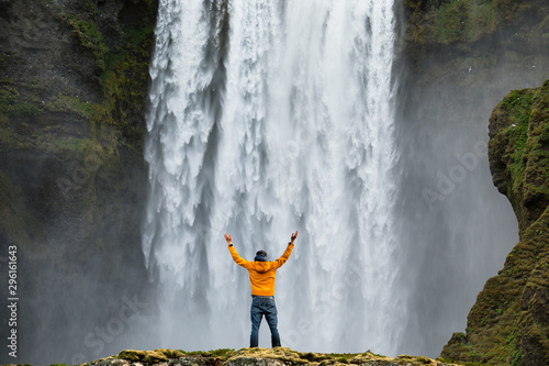 Fototapeta Naklejka Na Ścianę i Meble -  Man admirnig the beauty of iconic Skogafoss waterfall in Iceland, Europe.