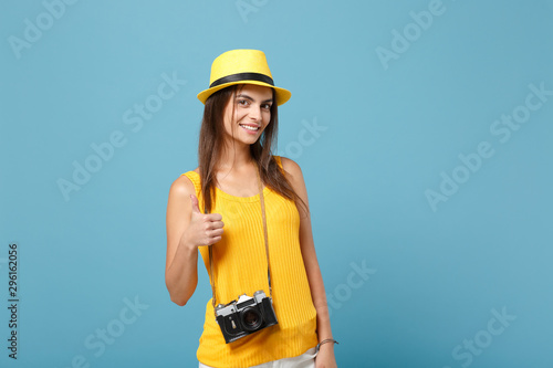 Traveler tourist woman in yellow summer casual clothes, hat with photo camera isolated on blue background. Female passenger traveling abroad to travel on weekends getaway. Air flight journey concept. © ViDi Studio