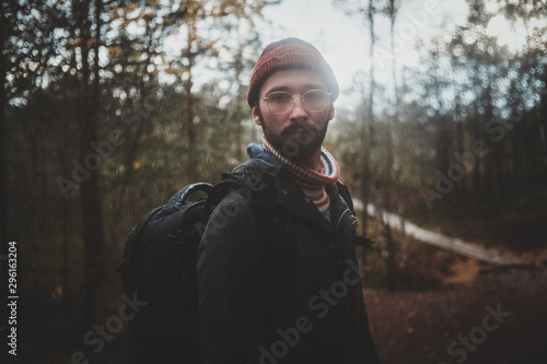 Portrait of young bearded hipster with backpack in the autumn forest.