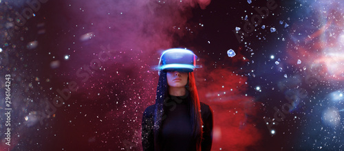 Beautiful woman with flowing hair in futuristic dress over dark space magic background. Girl in glasses of virtual reality. Augmented reality, game, future technology concept. VR.